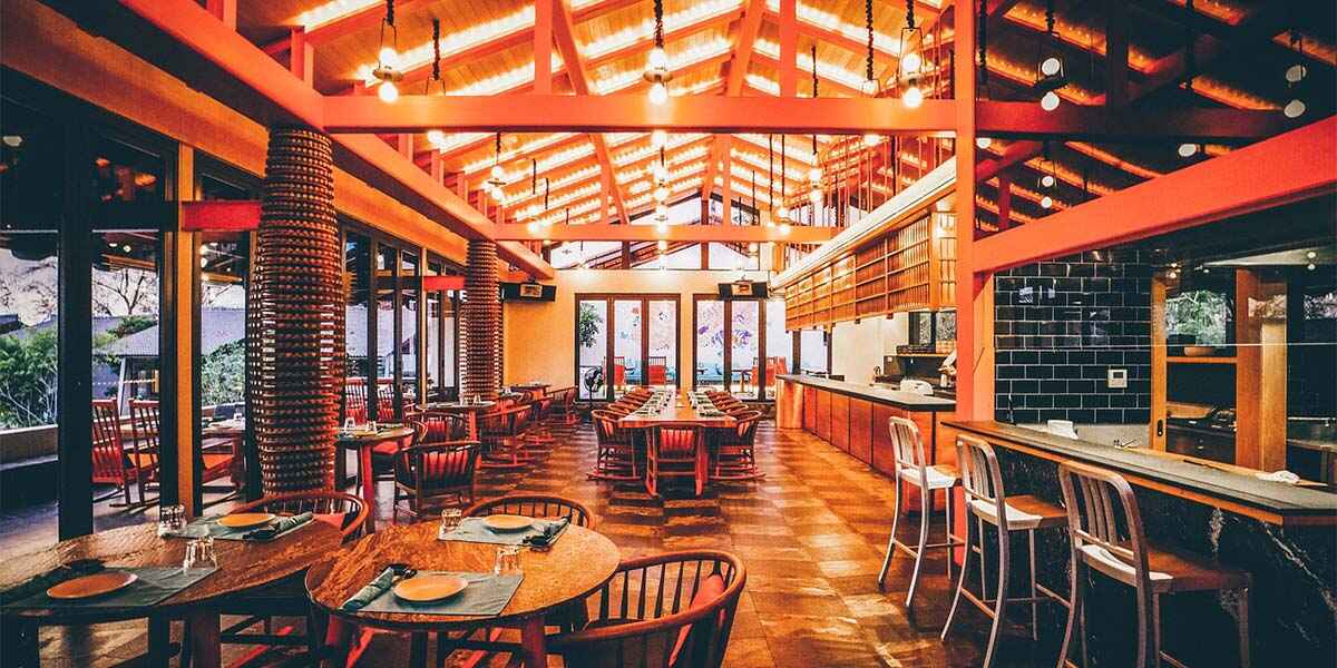 Cozy restaurant design with orange lighting, featuring wooden chairs and dining tables