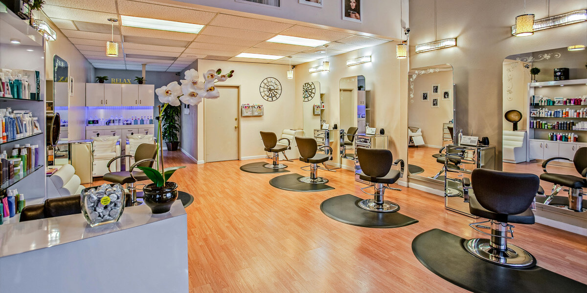 Modern salon interior design featuring five hairdresser chairs, a large mirror, wooden flooring, and cosmetics displayed