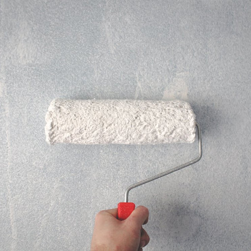 painting on a wall with paint roller from gray color