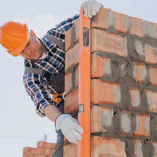 Mason wearing a safety helmet fix a bricks for masonry services in Dubai