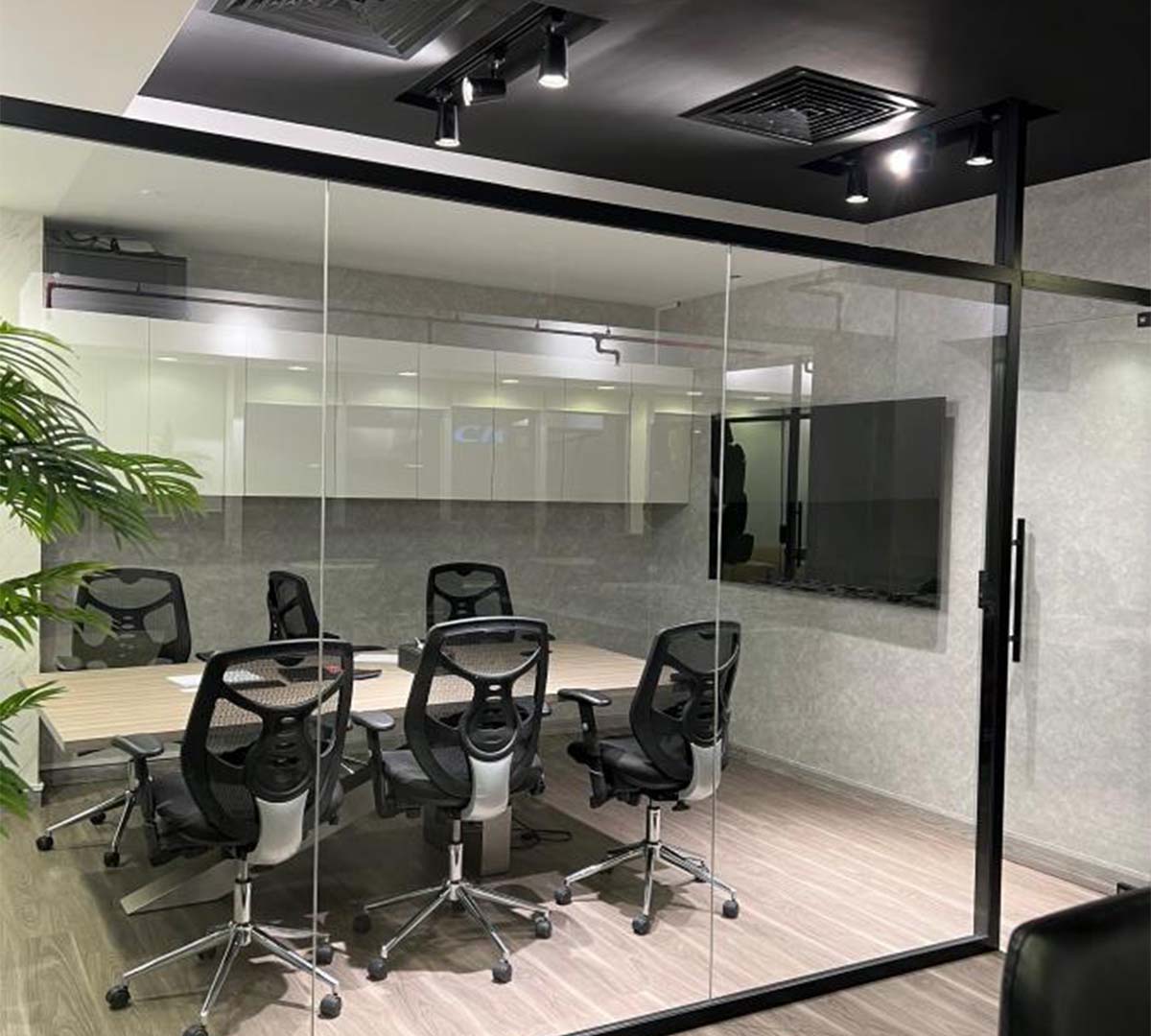 Black chairs placed in an office partitionaround a table